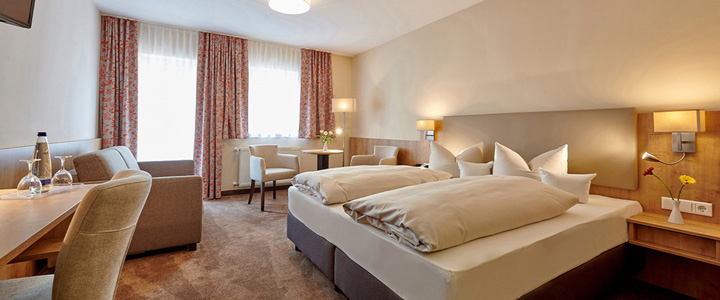 Das Doppelzimmer überzeugt mit edler Einrichtung in warmen Erdtönen. Schwere Vorhänge und eine stilvolle Beleuchtung schaffen ein behagliches, elegantes Ambiente.